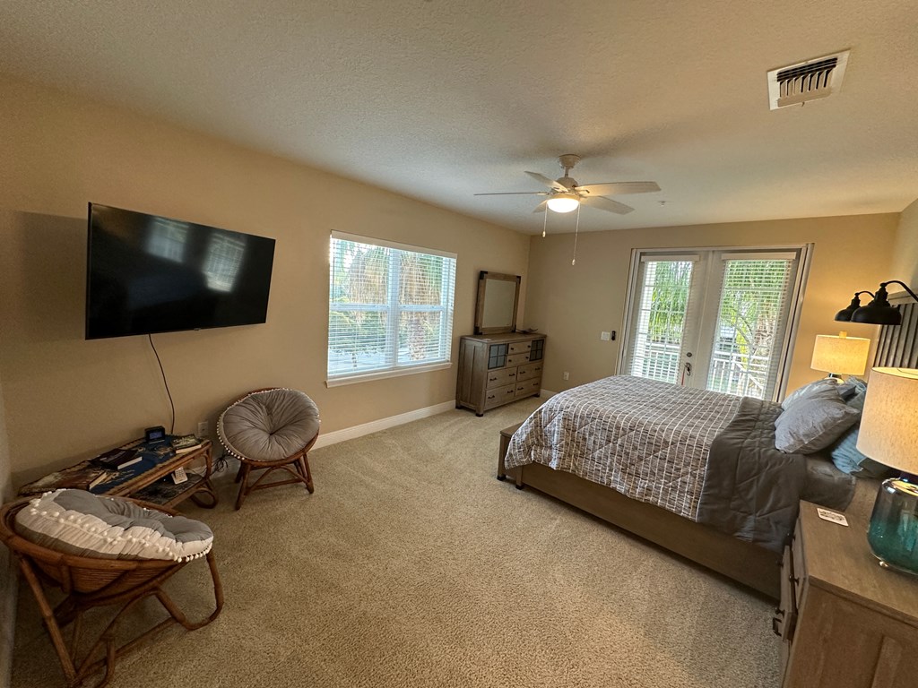 the master bedroom has a large tv and a king sized bed