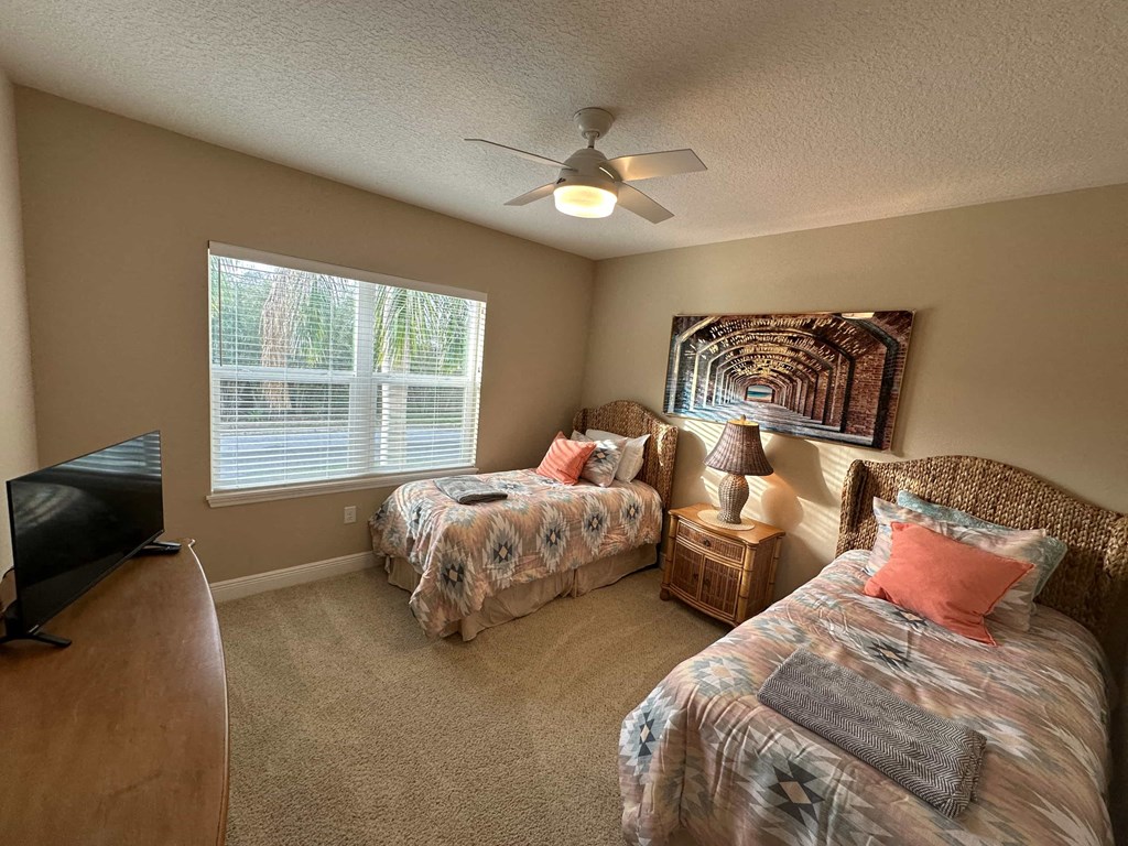 a bedroom with two beds and a ceiling fan