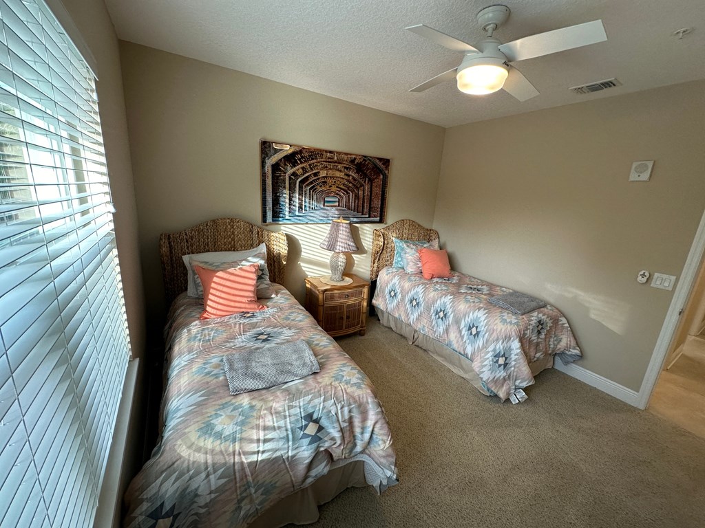 a bedroom with two beds and a ceiling fan