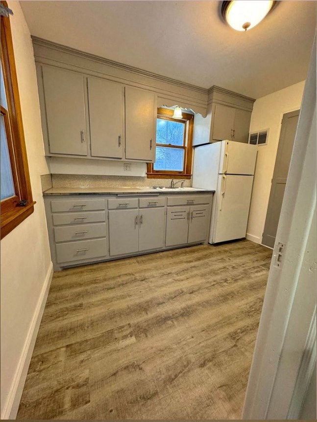 A kitchen with a white fridge and grey cabinets.