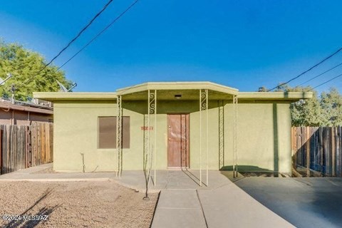 a small yellow house with a driveway and a door