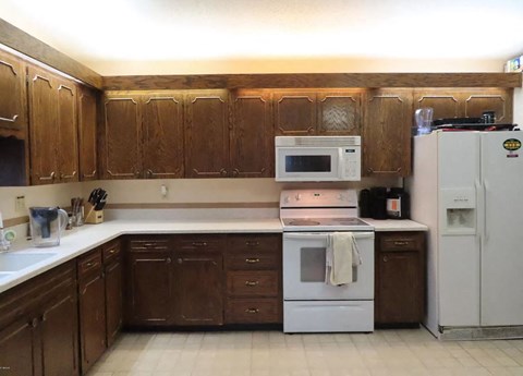 A kitchen with brown cabinets and a white refrigerator.