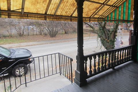 the front porch of a house with a car parked on the street