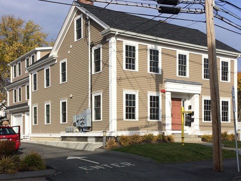 A two-story building with a red door and a red car parked in front.