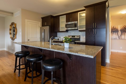 A kitchen with a granite countertop and black bar stools.