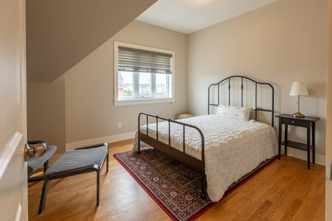 A bedroom with a bed, nightstand, and chair.