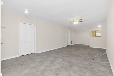 an empty living room and kitchen with a ceiling fan