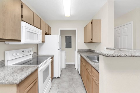 an empty kitchen with white appliances and granite counter tops