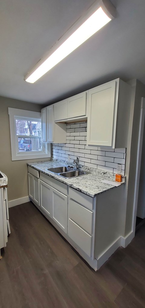 A kitchen with white cabinets and a granite countertop.