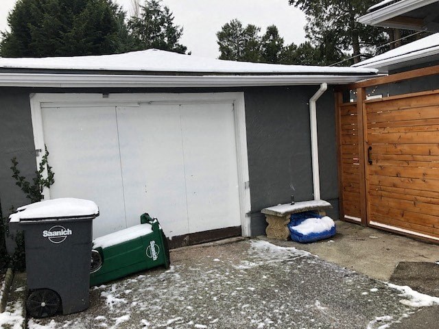 a garage with a white door and trash cans in the snow