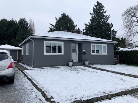 A grey house with a white car parked in front.