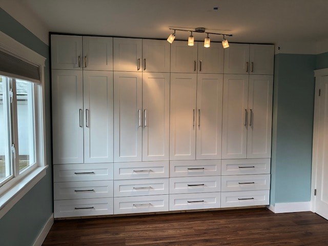 a row of white cabinets in a room with a wood floor