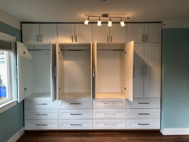 a large white closet with white drawers and