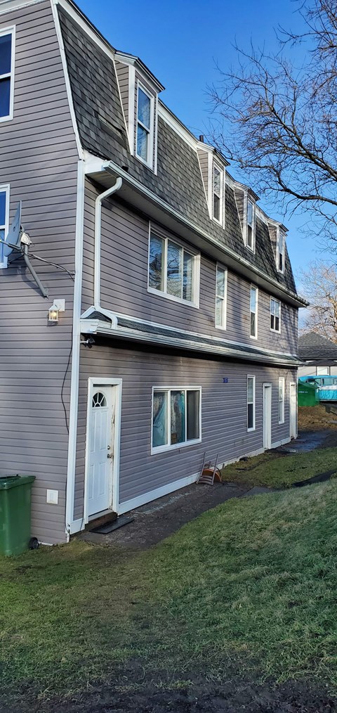 a gray house with a white door and a green lawn