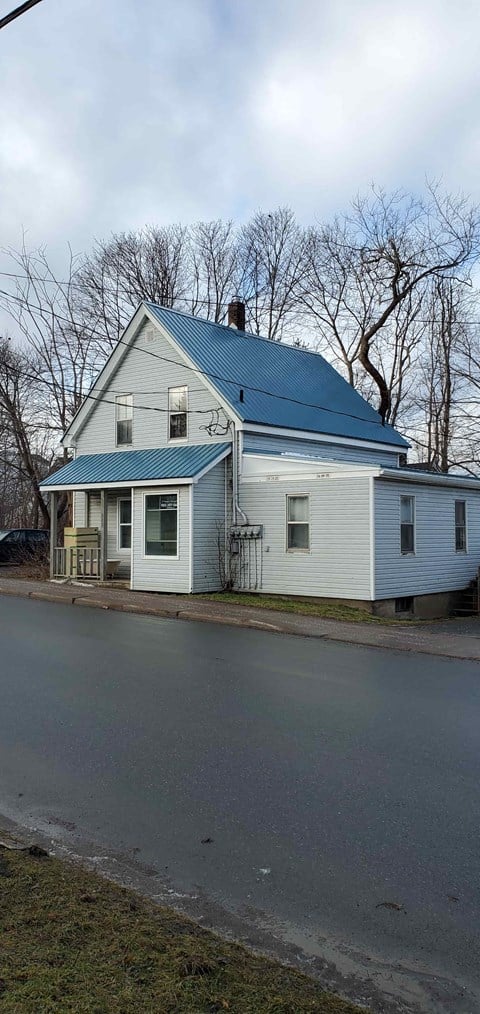 a white house with a blue roof on the side of a road