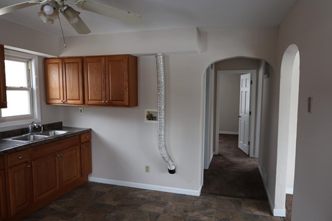 a kitchen with wooden cabinets and a sink and a ceiling fan