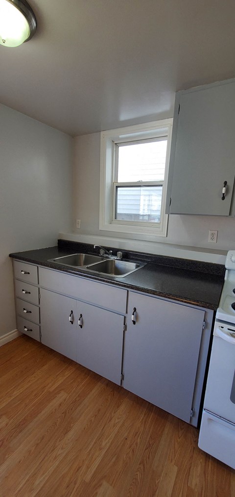 a kitchen with white cabinets and a sink and a window