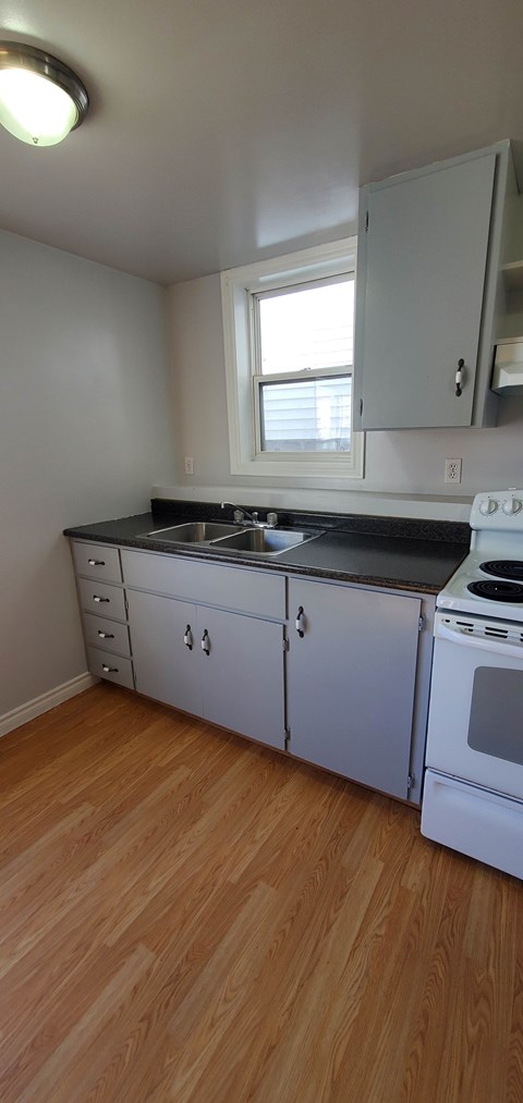 A kitchen with white cabinets and a black countertop.