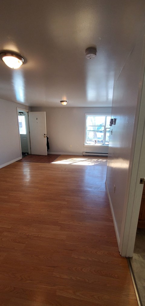 an empty living room with wood floors and a window