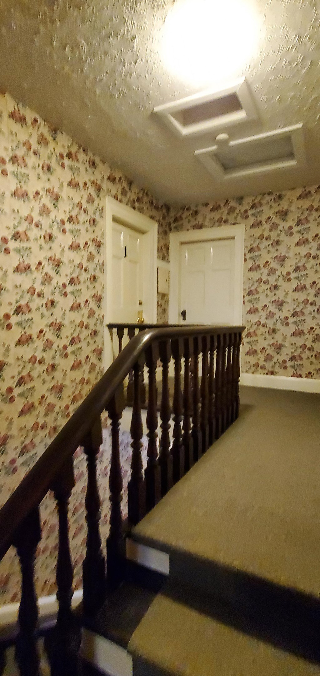 the landing of a staircase in a house with wallpaper and a door