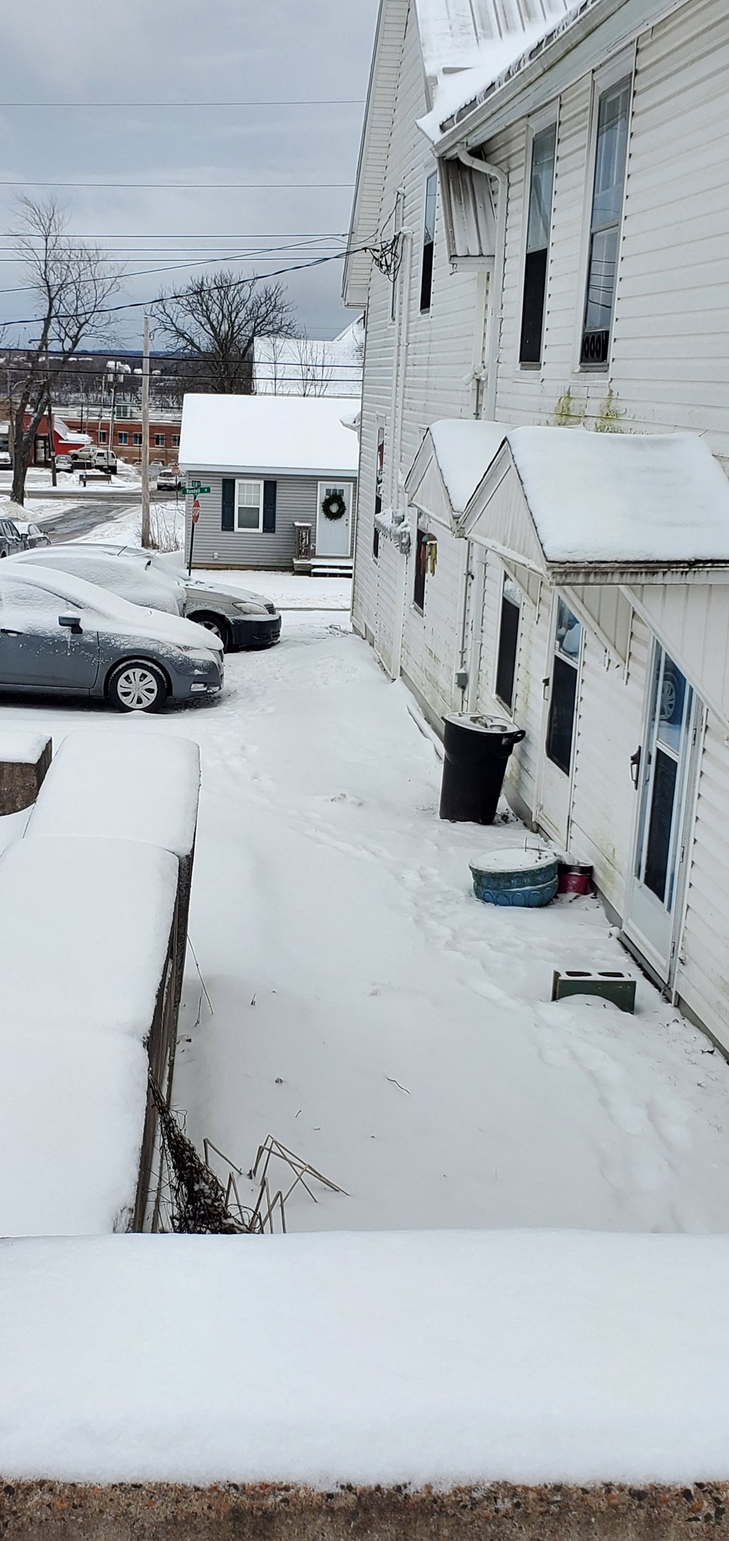 a snow covered street in front of a white house