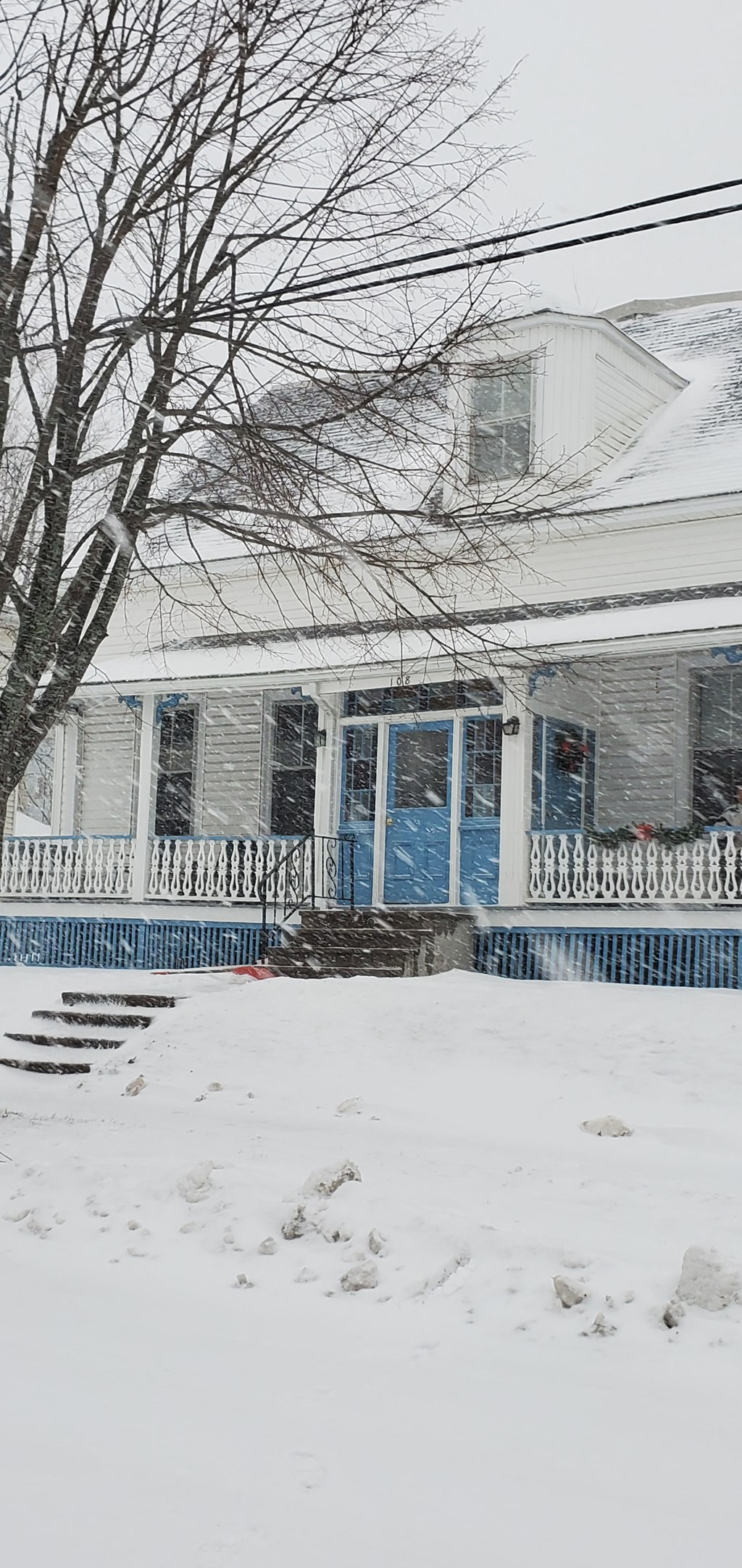 a house with a blue door and a porch covered in snow