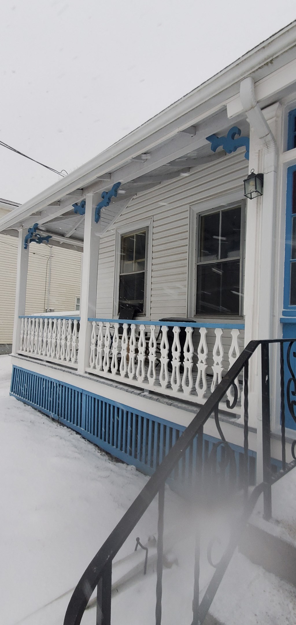 a blue and white house with a porch covered in snow