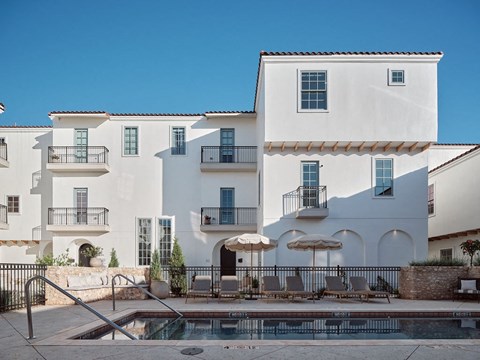 A white building with a pool in front.