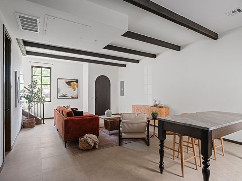 A living room with a red couch, a wooden table, and a painting on the wall.