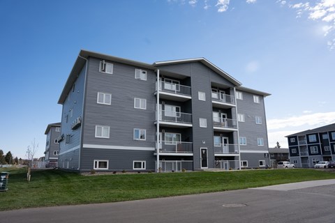 A large grey apartment building with multiple balconies and doors.