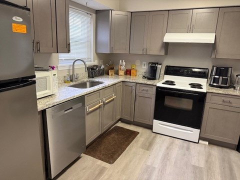 A kitchen with a black fridge, white oven, and a sink.