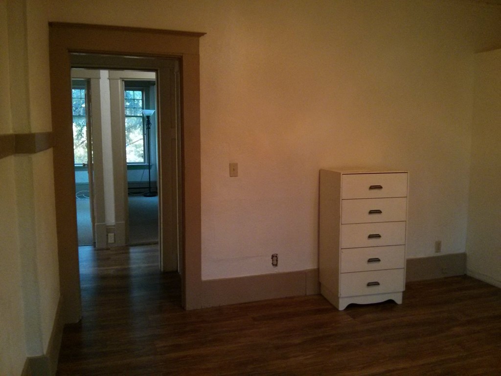 an empty room with a dresser and a door to a hallway