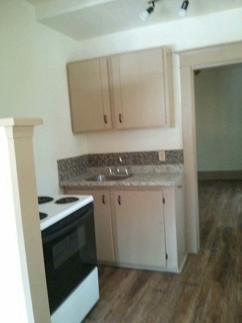 an empty kitchen with white cabinets and a stove