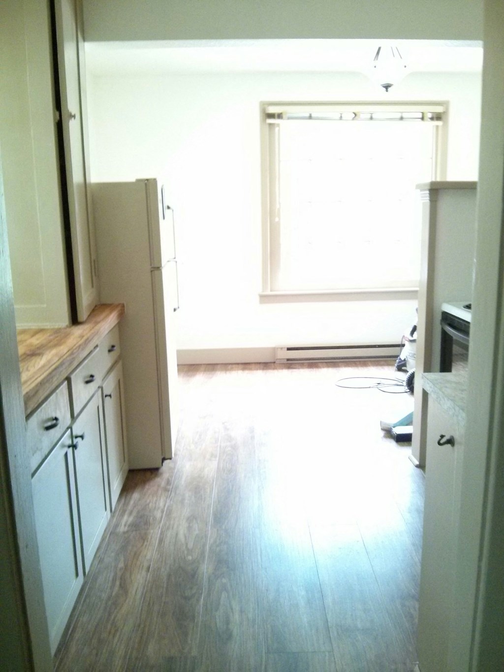 an empty kitchen with wood floors and white cabinets