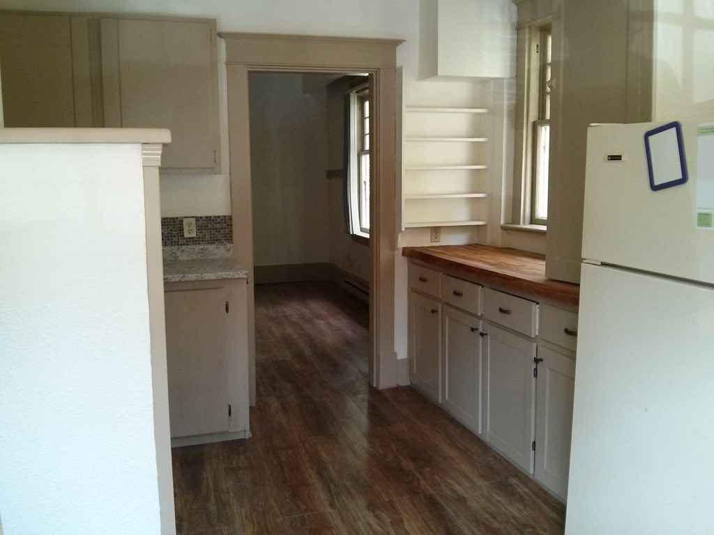 an empty kitchen with wooden floors and white cabinets