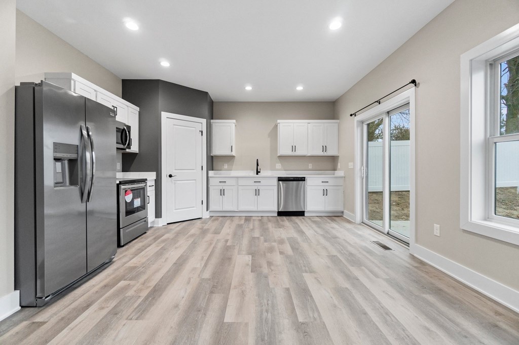 an empty kitchen with stainless steel appliances and white cabinets