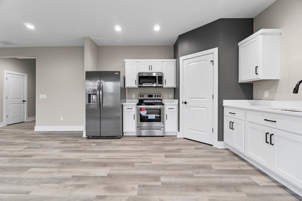 a large kitchen with white cabinets and stainless steel appliances