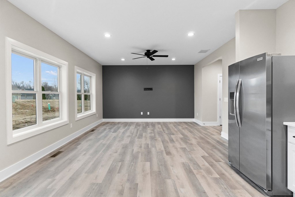 an empty room with a stainless steel refrigerator and a ceiling fan