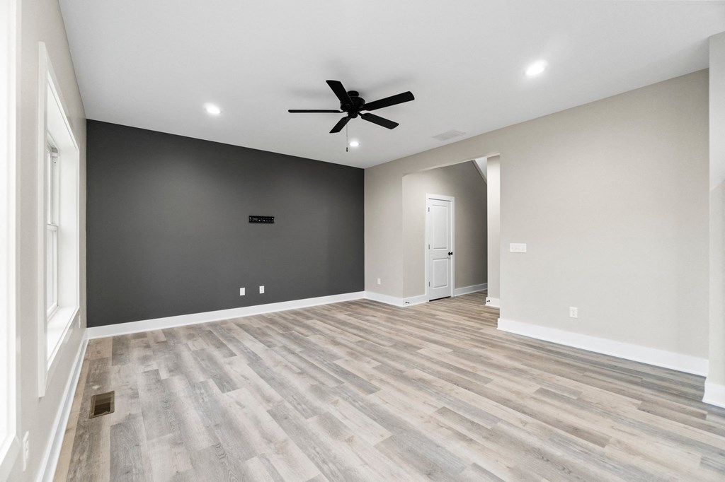 an empty living room with a ceiling fan and a door
