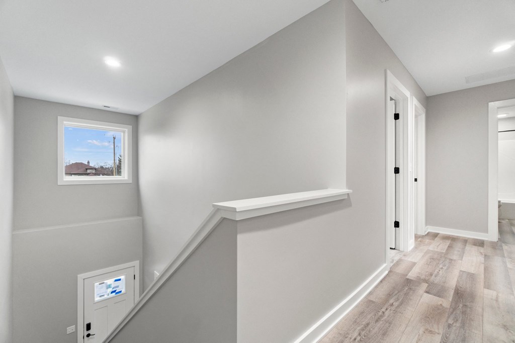 the landing of a staircase in a home with white walls and wood floors