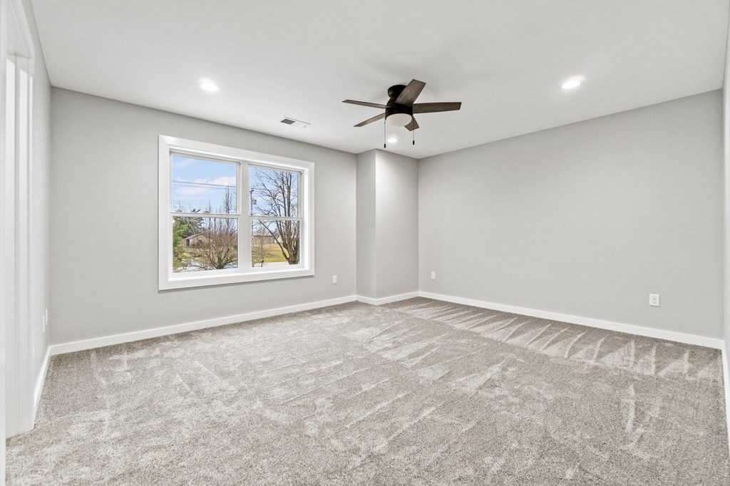 an empty living room with a ceiling fan and a window