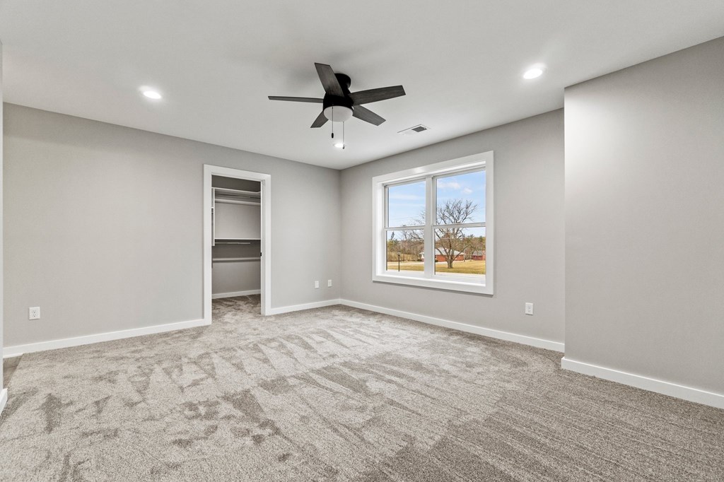 an empty living room with a ceiling fan and a window