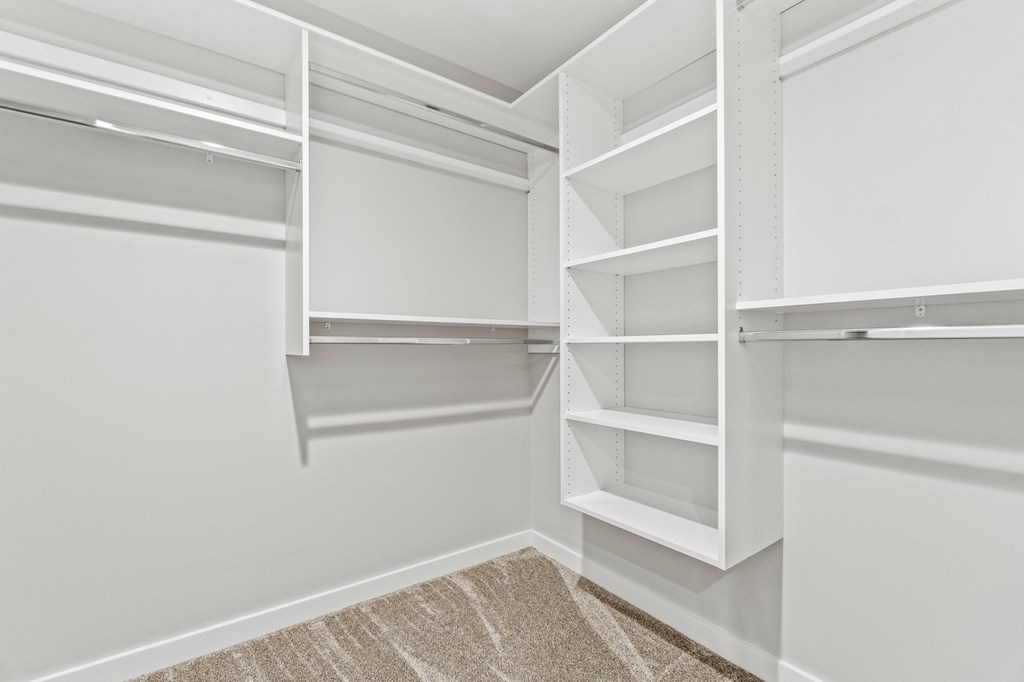the walk in closet of a manufactured home with white shelves and