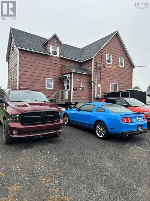 A red truck and a blue car are parked in front of a wooden house.