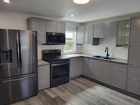 A kitchen with a stainless steel refrigerator and black oven.