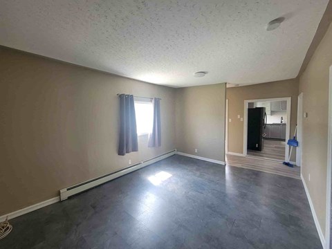 a empty living room with a gray floor and a window