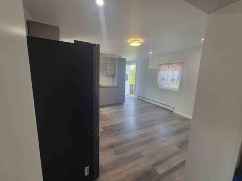 A black refrigerator is in the corner of a kitchen.