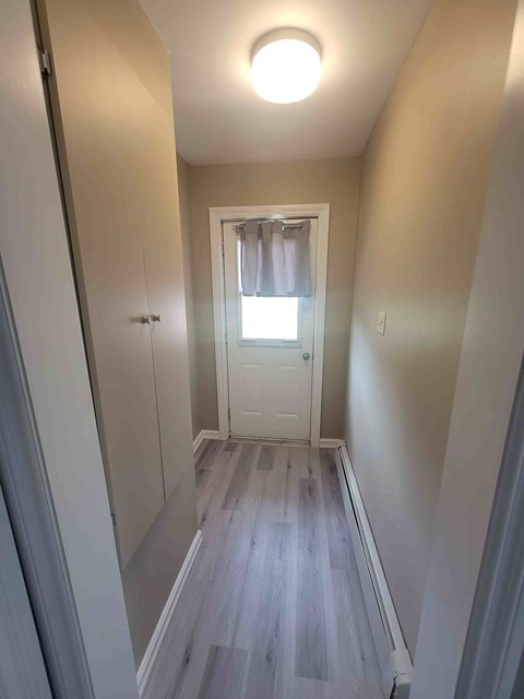 A hallway with a white door and a window.