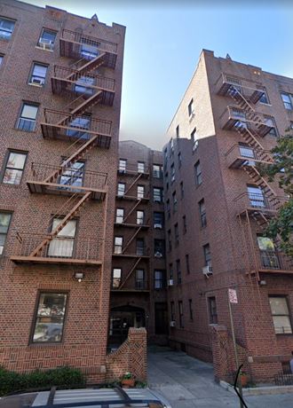 a view of two tall brick apartment buildings with fire escapes