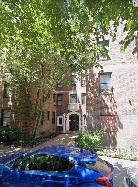 a blue car parked in front of a brick building
